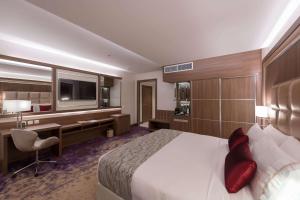 a hotel room with a bed and a desk and a television at Ramada by Wyndham Continental Jeddah in Jeddah