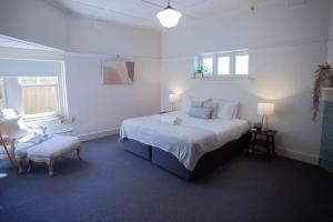 a white bedroom with a large bed and a chair at Parkside Spacious Central Family Retreat in Alfredton