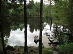 a boat parked next to a dock on a lake at Hide-A-Way Waterfront Cottages in Lake Luzerne