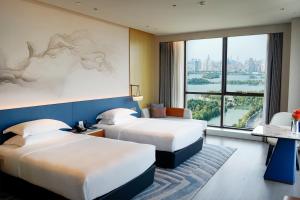 una camera d'albergo con due letti e una grande finestra di 南昌象湖格兰云天大酒店 a Taohua