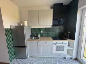 a small kitchen with white cabinets and a sink at Apartament Green Powiśle in Kwidzyn +5 photos