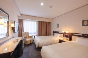 a hotel room with two beds and a desk at Sasebo Washington Hotel in Sasebo