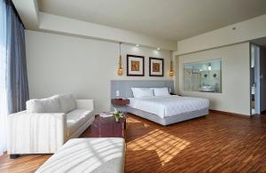 1 dormitorio con cama blanca y sofá en The Sintesa Jimbaran Bali, en Jimbaran