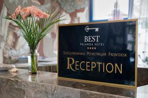 a sign sitting on a table with a vase of flowers at Best Palanga Hotel in Palanga