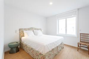 a bedroom with a bed and a window and a chair at Cascais Center Luxury Triplex in Cascais