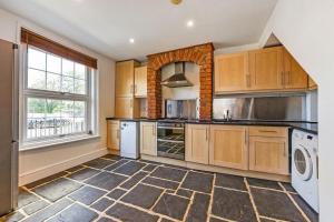 a kitchen with wooden cabinets and a brick wall at Winchester City House in Winchester