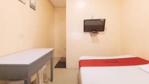 a hospital room with a desk and a tv on the wall at RedDoorz at LYOTO Bed and Breakfast near NAIA Terminal in Manila