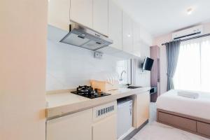 a small white kitchen with a bed in a room at Comfy and Best Choice Studio at Sky House BSD Apartment By Travelio in Tangerang