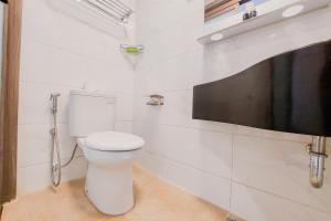 a bathroom with a toilet and a tv on the wall at Comfy and Best Choice Studio at Sky House BSD Apartment By Travelio in Tangerang