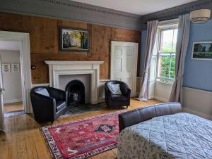 a living room with two chairs and a fireplace at The Lawns House in Holt