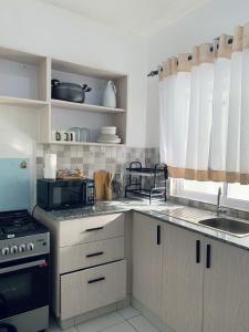 Una cocina con gabinetes blancos, un fregadero y una estufa. en Wokabi Homes, en Mombasa 33 fotos más