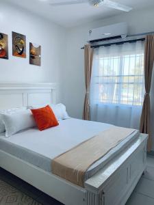 Un dormitorio con una gran cama blanca con ventana. en Wokabi Homes, en Mombasa