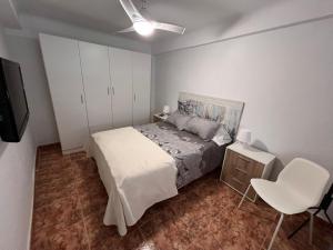 ein Schlafzimmer mit einem Bett, einem Fernseher und einem Stuhl in der Unterkunft Apartamento en el centro de Nerja in Nerja
