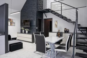 a dining room with a table and chairs and a staircase at Béke 10 Apartmanház in Villány