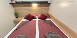 a bed in a small room with red pillows at Mobile Home Maja in Pirovac