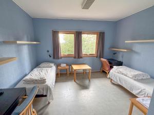 a room with two beds and a table and a desk at Agder Folkehøgskole - Gjestehus in Kristiansand