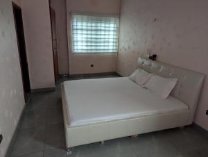 a large white bed in a room with a window at Domicile Cotonou in Cadjèhoun