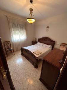 a bedroom with a bed and a table and a chandelier at Piso completo, acogedor y cerca del centro in Baeza