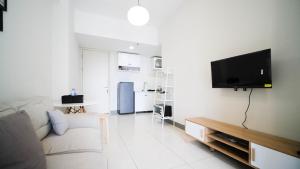 a living room with a couch and a tv on a wall at Spacious 2BR Connected to Mall at Anderson Supermall Mansion Apartment By Travelio in Surabaya