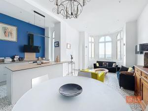 un salon avec une table blanche et un mur bleu dans l'établissement Les Lutins - sur la plage, à Wimereux