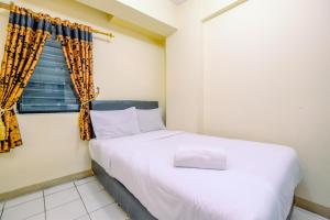 a bedroom with a white bed and a window at Comfort and Cozy Living 2BR at Cibubur Village Apartment By Travelio in Depok