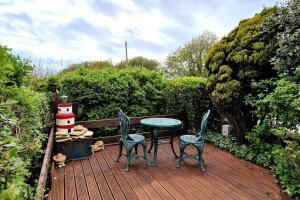 a deck with a table and two chairs and a lighthouse at Galley View Ardfield Clonakilty in Clonakilty