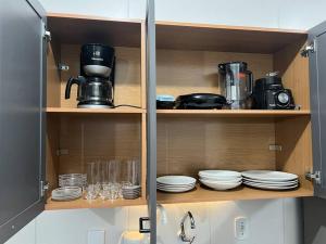 a cupboard with plates and cups and a coffee maker at Sinta-se em casa! in Sorocaba