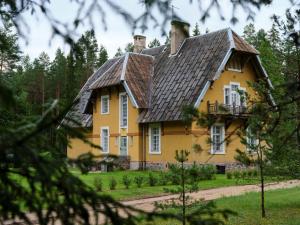 a yellow house with a black roof at Bergervilla Boutique Guest House & SPA in Mežmuiža