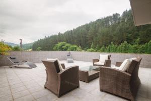 eine Terrasse mit Korbstühlen und einem Tisch auf der Terrasse in der Unterkunft Beautiful townhouse 20km from Bilbao in Laudio/Llodio