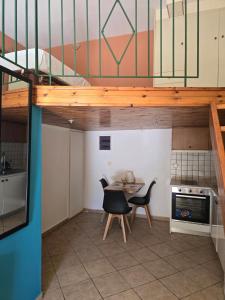 a loft bed in a tiny kitchen with a table and chairs at Μεζόνετα AIKATERINI N 13 in Chios