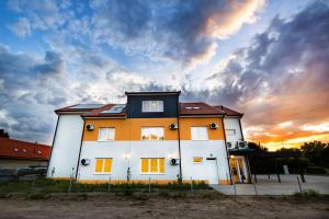a large white house with a sunset in the background at Gellén Panzió in Debrecen