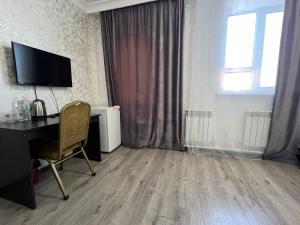 a room with a desk with a computer and a window at Rush Hotel in Atyrau