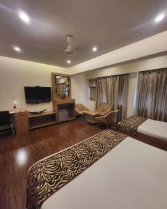 a hotel room with a bed and a television at Hotel Maharana Inn Chembur in Mumbai