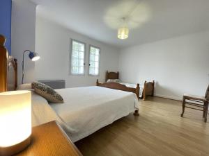 ein weißes Schlafzimmer mit einem Bett und einem Stuhl in der Unterkunft Chocobia in Arbonne