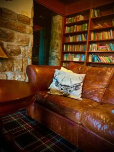 a brown leather couch with a pillow on it at Loch Ness Lodge Hotel in Drumnadrochit
