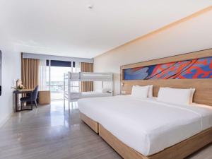 a hotel room with a large bed and a desk at Novotel Phuket City Phokeethra in Phuket Town