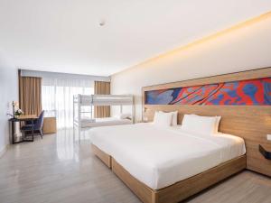 a bedroom with a large bed with a painting on the wall at Novotel Phuket City Phokeethra in Phuket Town
