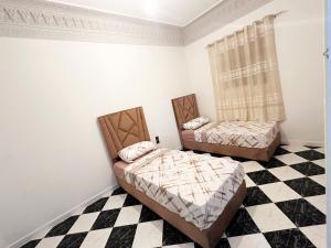 two beds in a room with a checkered floor at FTOUH House in Tangier