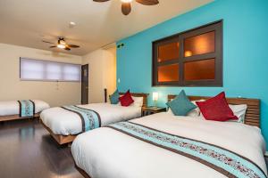 two beds in a room with blue walls at 1688House美ら海 in Motobu