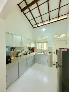 Una cocina grande con gabinetes blancos y un refrigerador. en Serene Lush Holiday Home, en Tangalle
