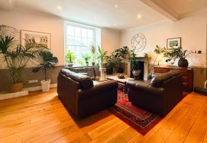 a living room with two leather couches and plants at The Western in St Ives