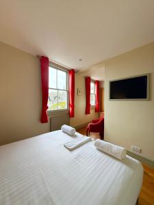 a bedroom with a large white bed with red curtains at The Western in St Ives