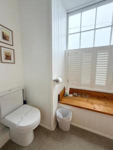 a white bathroom with a toilet and a window at The Western in St Ives