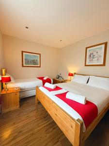 a bedroom with two beds with red and white sheets at The Western in St Ives