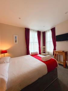 a bedroom with a large bed with red curtains at The Western in St Ives