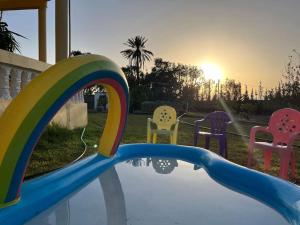 a pool with chairs and a rainbow in a backyard at Countryside's Tiny House in Ben Slimane
