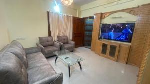 een woonkamer met een bank en een tv bij Nisarga Jagannath Manor in Bellary +6 foto's