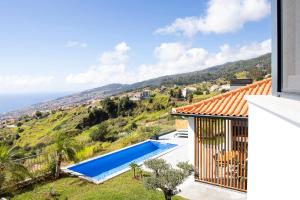 eine Villa mit Swimmingpool und Blick auf das Meer in der Unterkunft Vila Rouxinol in Arco da Calheta