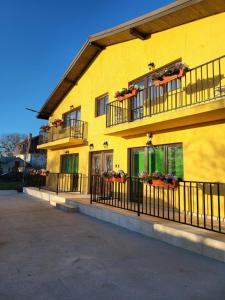a yellow building with balconies and flower boxes on it at Casa Ratiu 3 Stele Airport Bucharest Therme Bucharest in Baloteşti