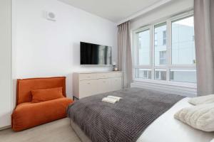 a bedroom with a bed and a chair and a television at Studio Śląska z Siłownią w Gdańsku by Noclegi Renters in Gdańsk
